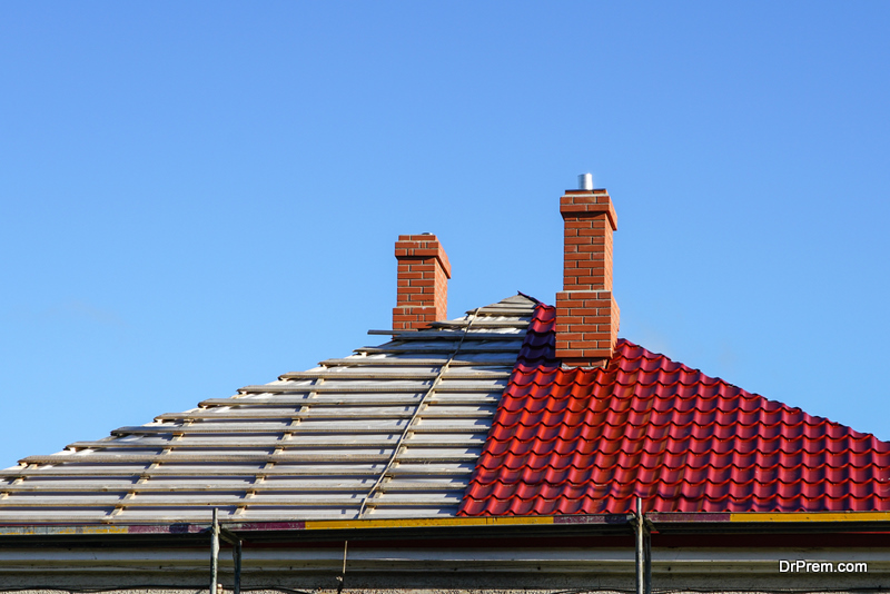 replacement of the roofing of a residential house on a background of blue sky, half changed, half not yet