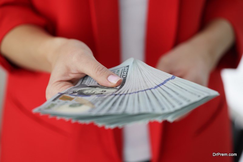 Woman in red jacket holding lot of American dollar bills